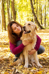 Beautiful woman with a golden retriever dog in autumn park