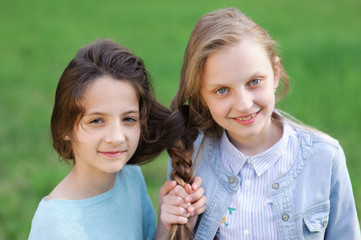concept of friendship two beautiful girls with connected hairs outdoors portrait