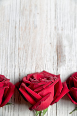 Three Red roses on light wooden background with copy space, top view , vertical composition - Image