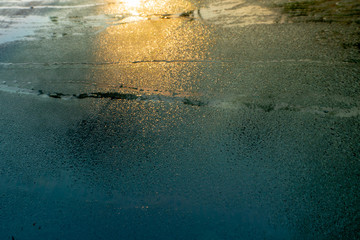 Water drops on the car window on a cold morning and the reflection of the sunrise can be seen on the window. It looks like snow on the ground. (2)