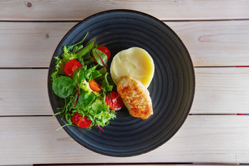 Fried chicken patty with mashed potato and fresh arugula, tomato and spinach