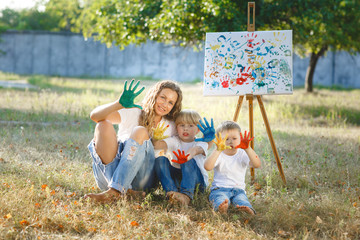 Young attractive mother having fun with her children at the park. Cheerful family having fun outdoor. Mom plays with her kids. Colorful background.