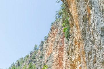 Climbing wall at the hillside of a rocky mountain. Carabiners ready to be used by the climbers. Sunny day of summer with natural light. Soft background