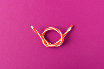 Flexible pencil . Isolated on purple background. Bending pencil.