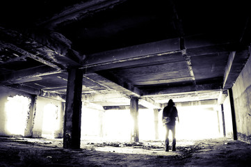 Silhouette of a young man going to bright light in an abandoned and ruined building.