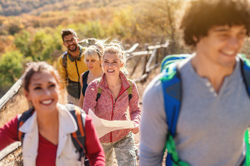 Hikers walking on the glade. Selective focus blonde woman holding map. Autumn time.