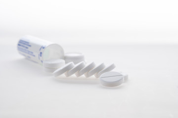 Antipyretic tablets, painkillers scattered on the table on a white background