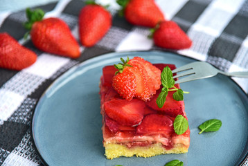 Classic traditional German Strawberry Cake on blue dish with mint leaf and fresh strawberry.