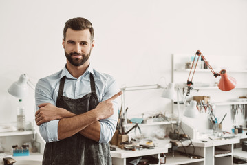 I made my choice, and you? Portrait of cheerful male jeweler wearing apron, smiling and pointing finger at copyspace