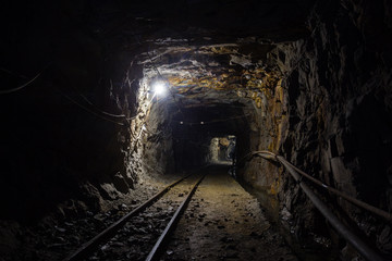 Underground gold ore mine shaft tunnel gallery passage with rails and light