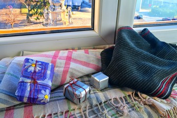 Holidays, winter, celebration and still life concept - window sill, gift boxes, warm scarf at home. Romantic still life