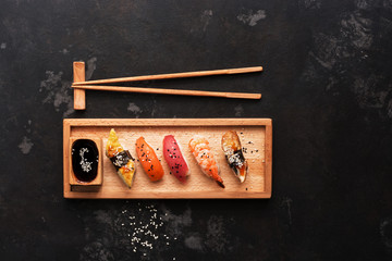 Close up of sashimi sushi set with chopsticks and soy sauce, dark stone background. Top view, copy space.
