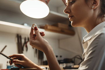 Perfection. Close up of young female jeweler looking and inspecting a ring.
