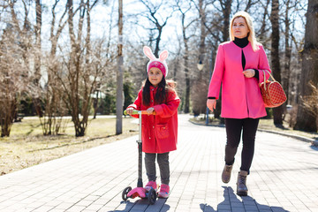 Portrait of young caucasian family walking along street little girl with scooter