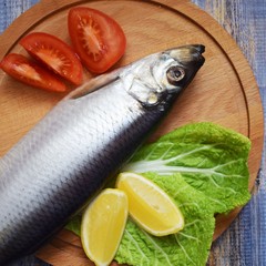 Delicious herring with lemon and tomatoes on lettuce leaves.
