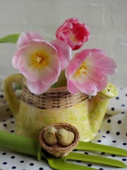 three tulips in pots and plaster decor in the form of birds in the nest on a white background and fabric with polka dots