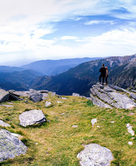 Back view of tourist couple, man and girl stand on rocky mountain top enjoying breathtaking summer mountain panorama. Tourism, traveling lifestyle concept. motorcyclists, vertical photo, Romania