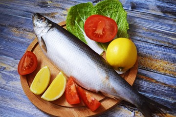Delicious herring with lemon and tomatoes on lettuce leaves.