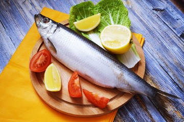 Delicious herring with lemon and tomatoes on lettuce leaves.