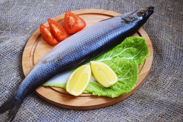 Delicious herring with lemon and tomatoes on lettuce leaves.