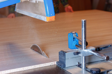 The sawing of the big wood panel on the circular saw table tool. Wooden furniture production on the...