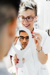 Young optometrist helps customer to choose right eyeglasses