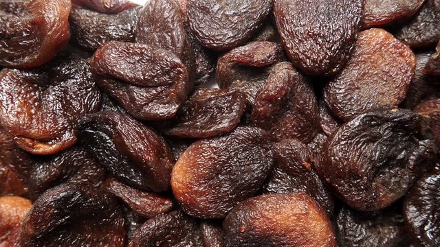 Brown dark color dried apricots as natural food background. Top view. Healthy food. Organic fruit not treated with sulfur dioxide.