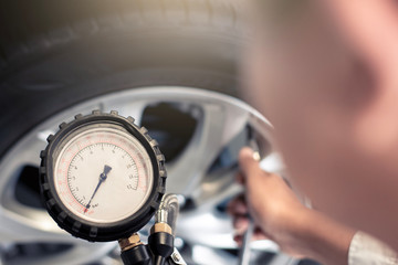Asian man car inspection Measure quantity Inflated Rubber tires car.Close up hand holding machine...