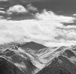 Snowy winter mountains and sky with sunlight clouds
