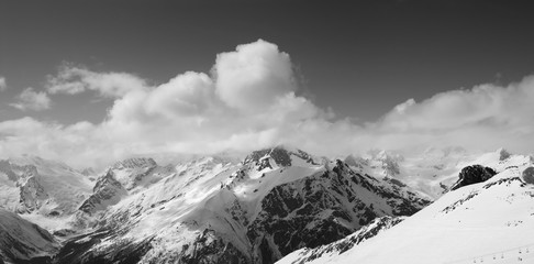Black and white panorama of ski resort and snowy mountains in clouds
