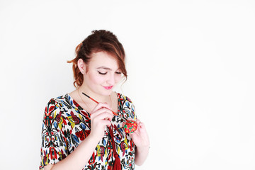 woman paints an Easter egg with paints on a white background