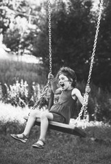 Black and white portrait of Beautiful little girl smiling on swing at summer day, Happy childhood concept. Soft focused.