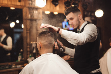 Professional barber splashes water on a head of client
