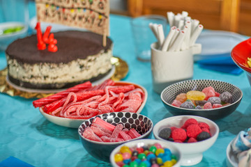 Colorful sweets on birthday table with blue tablecloth