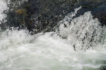 Natural texture of foamed water surface. Rapids of river close-up. Fast flow in mountain creek. Background of clean water waves with copy space. Textured foam of shiny stream. Fast river texture.