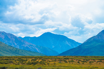 Spectacular view of giant mountains under cloudy sky. Huge mountain range at overcast weather. Wonderful wild scenery. Atmospheric dramatic highland landscape of majestic nature. Scenic mountainscape.