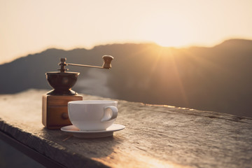 Hot morning cup of coffee with mountains background at sunrise with copy space