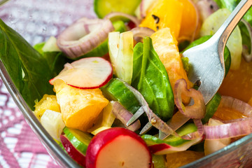 Salad with spinach leaf, onion, radish, cucumber and orange.
