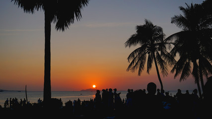Obraz premium Silhouetted People Relaxing on Sunset Beach. Travel concept