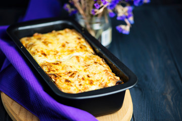 meat cheese pie in baking dish on a dark wooden background
