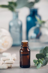 Eucalyptus essential oil and fresh leaves, white capsules pills on the stone board.