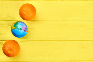 Fresh oranges, globe and copy space. Two oranges and one globe on colorful wooden background with text space.