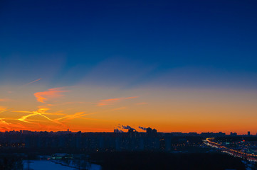 Naklejka premium Orange clouds with aircraft trails sky background and city light midnight evening time