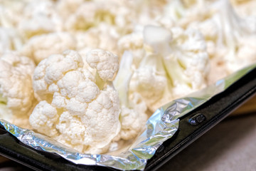 Pieces of cauliflower on a baking sheet (foil). Healthy food close-up.
