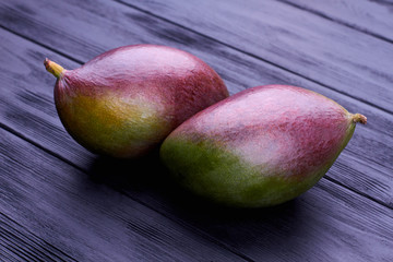 Whole fresh mangoes close up. Two organic mangoes on wooden surface. Tasty and nutritious fruit.