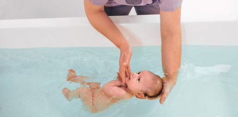 Swimming instructor teaches infant baby to swim. Aquatic therapy for infant baby