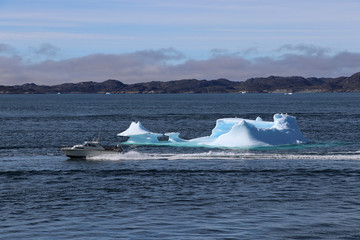 The boat rushes at high speed past an iceberg in the blue bay of Nuuk, Greenland