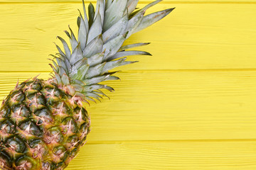 Fresh organic pineapple on wooden background. Tropical ananas fruit on yellow wood with copy space. Health benefits of pineapple.