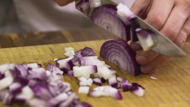 Chef chopping red onion for salad