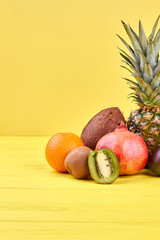 Composition with tropical fruits and copy space. Group of delicious exotic fruits on yellow background and text space.